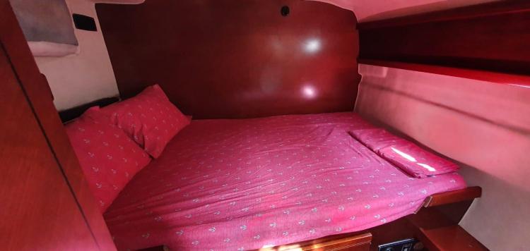 Cozy cabin interior of 1999 Fountaine Pajot Bahia 46 with red bedding.