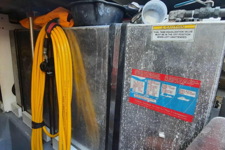 Engine room of 2000 Carver 530 Voyager Pilothouse with yellow hose and caution signs.