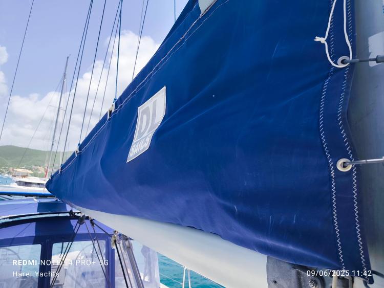 Beneteau Cyclades 43.3 sailboat with blue sail cover, 2005 model, docked in sunny marina.