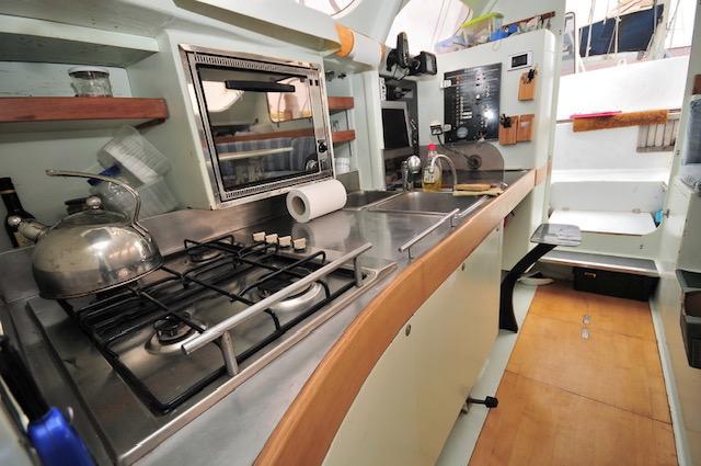 Compact kitchen in a 2005 Custom Polynésie 42 yacht with stove, sink, and storage.