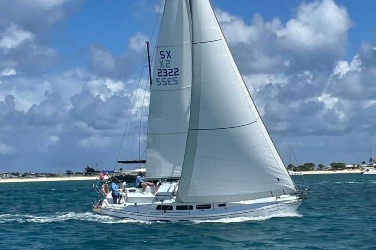 Sailboat Dufour CATALINA 1986 cruising on blue ocean under cloudy sky.