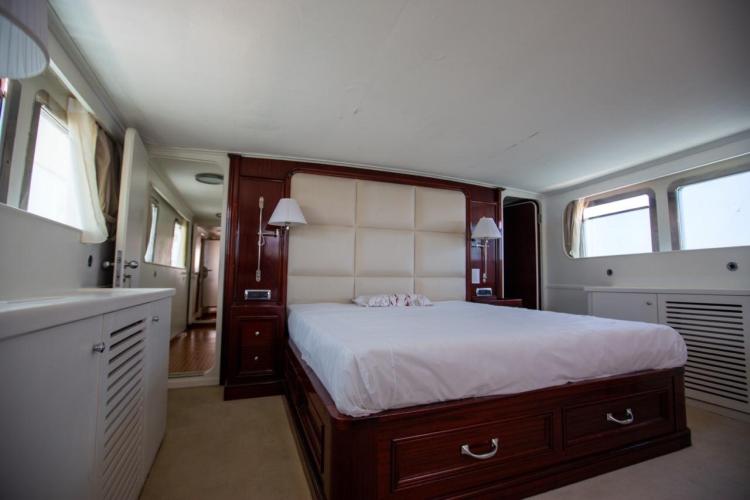 Luxurious bedroom interior on a 1972 Benetti 33 yacht with elegant wood accents.