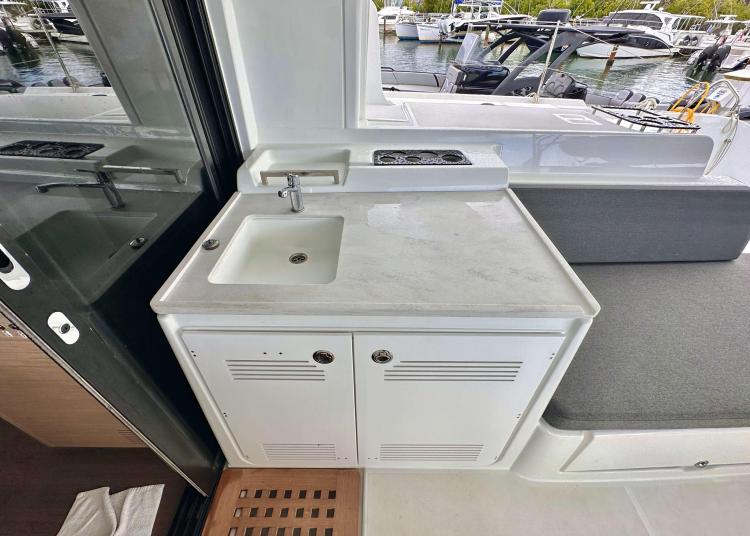 Modern kitchenette on 2023 Lagoon 46 yacht with sink and storage, docked at marina.