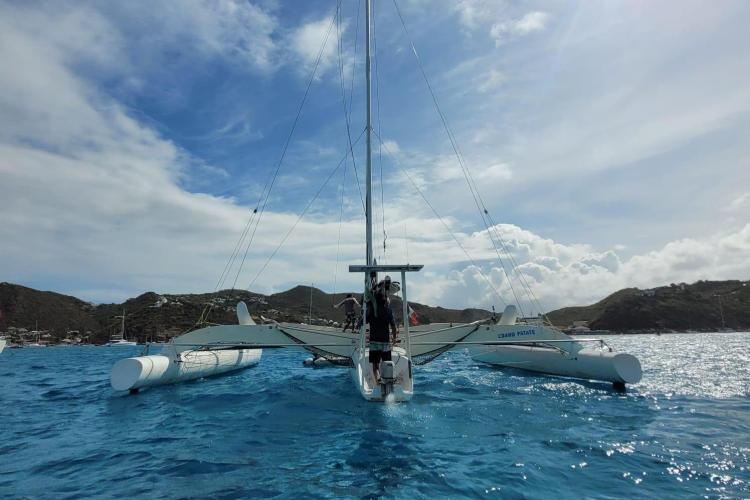 1994 Coulombel Trimaran sailing on clear blue waters under a partly cloudy sky.