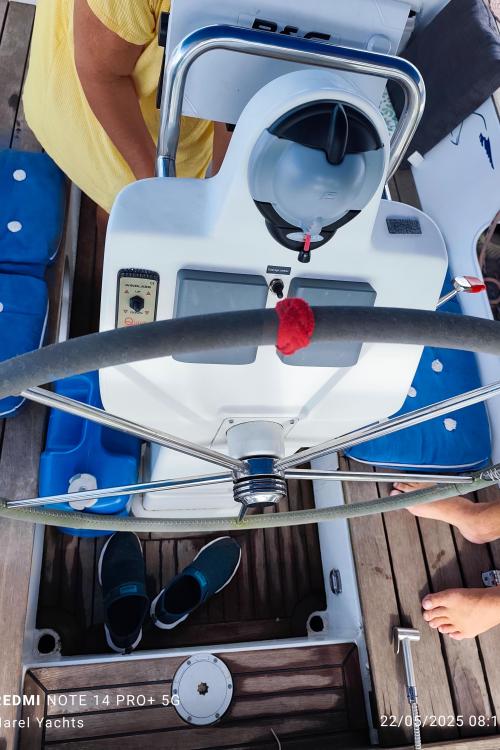 Steering wheel of a 2019 Custom Patago 40 yacht with blue seating and wooden deck.