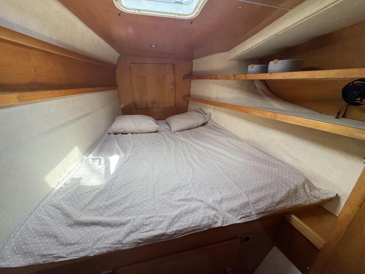 Cozy cabin interior of 2006 Fountaine Pajot Bahia 46 with bed and shelves.