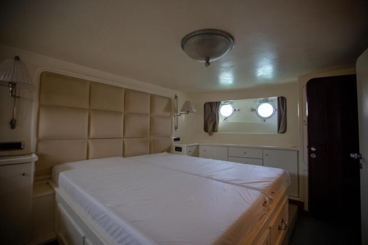 Luxurious bedroom interior of 1972 Benetti 33 yacht with porthole windows.