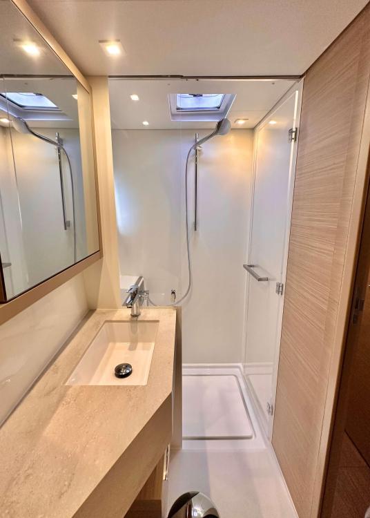 Modern bathroom in 2023 Lagoon 46 yacht with shower and sleek vanity.