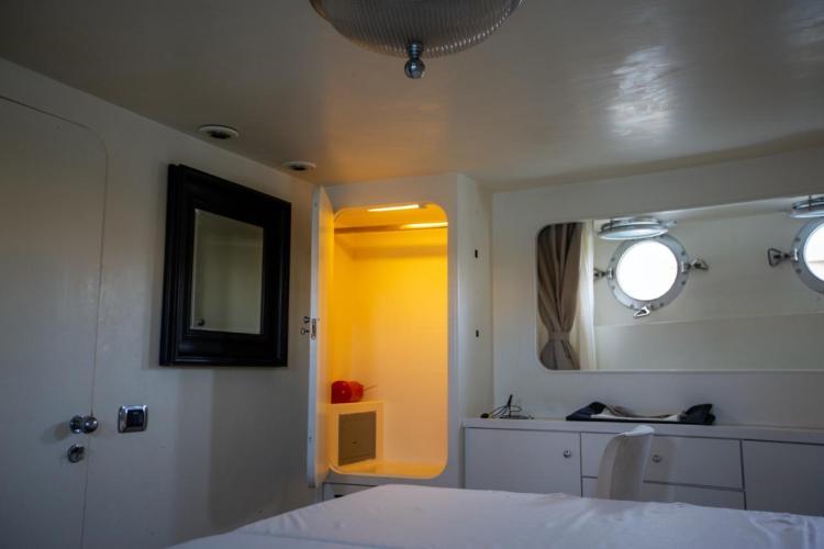 Interior of 1972 Benetti 33 yacht cabin with porthole, mirror, and open closet.