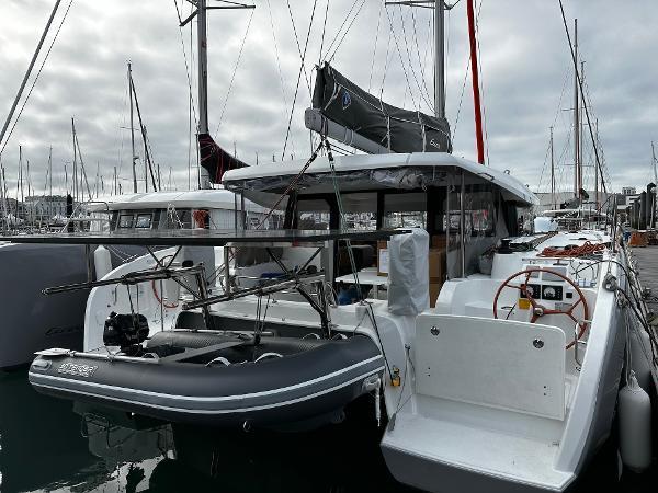 2024 Excess 11 catamaran docked with inflatable boat, overcast sky, marina setting.