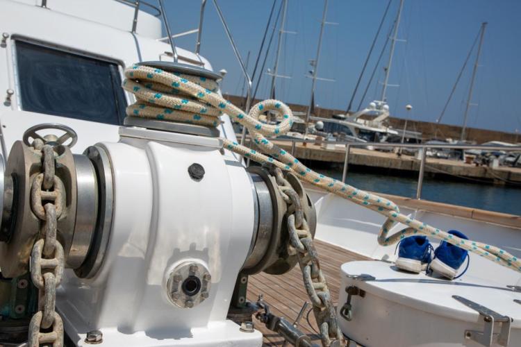 Deck of 1972 Benetti 33 yacht with anchor chain and rope, marina background.