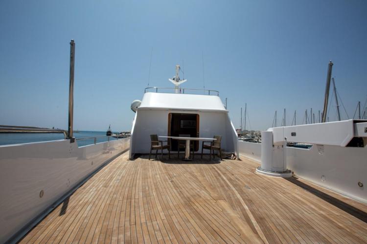 1972 Benetti 33 yacht deck with wooden flooring and outdoor seating, docked at a marina.