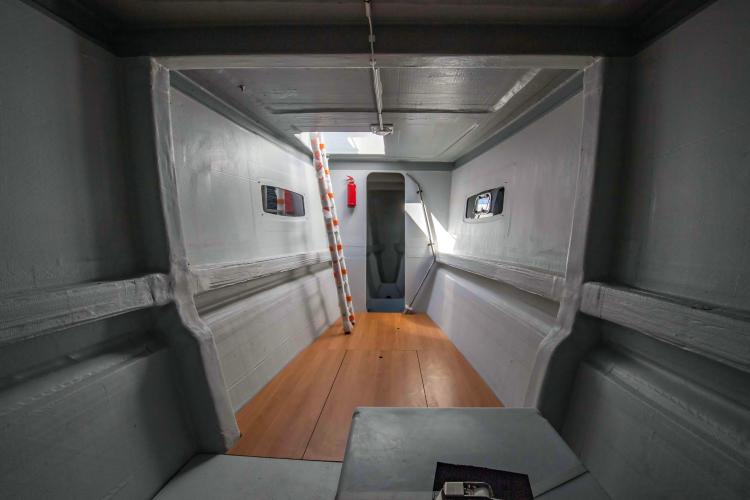 Interior of 2026 Custom DAYCHARTER boat with wooden flooring and ladder access.