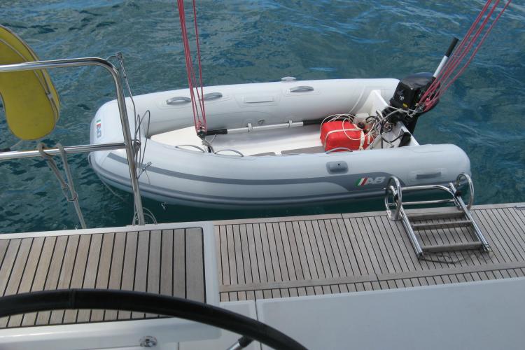 Inflatable dinghy alongside 2019 Beneteau Oceanis 46.1 yacht, with wooden deck and ladder.