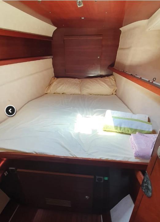 Cozy cabin interior of 1999 Fountaine Pajot Bahia 46 catamaran with bed and wooden accents.