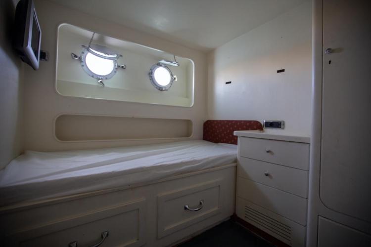 Cozy cabin interior of 1972 Benetti 33 yacht with portholes and storage.