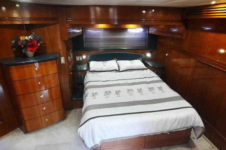 Luxurious bedroom interior of 2000 Carver 530 Voyager Pilothouse yacht with wood paneling.