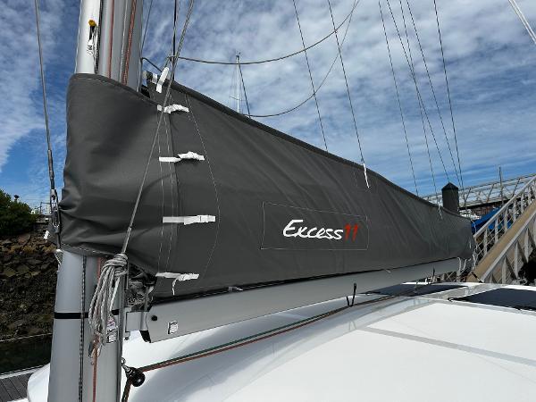2024 Excess 11 sailboat with gray sail cover, docked under a blue sky.