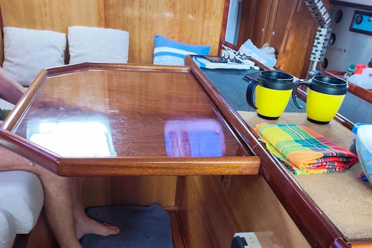 Interior of 2019 Custom Patago 40 yacht with wooden table, cushions, and mugs.