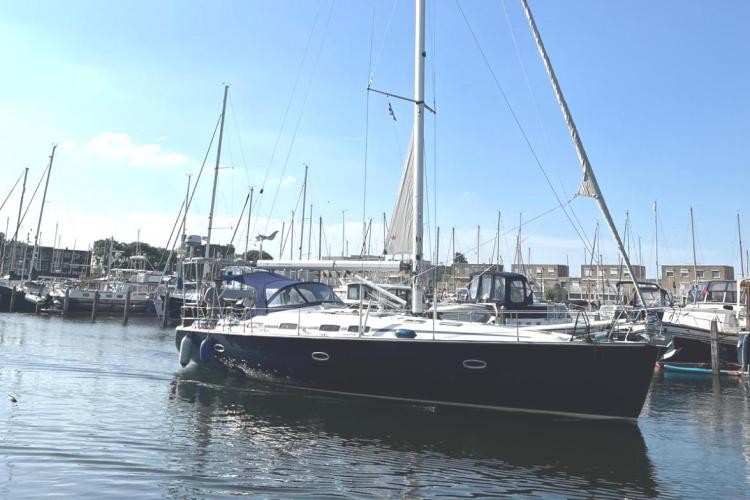 2006 Bavaria Cruiser 46 sailboat docked in a marina under clear blue skies.