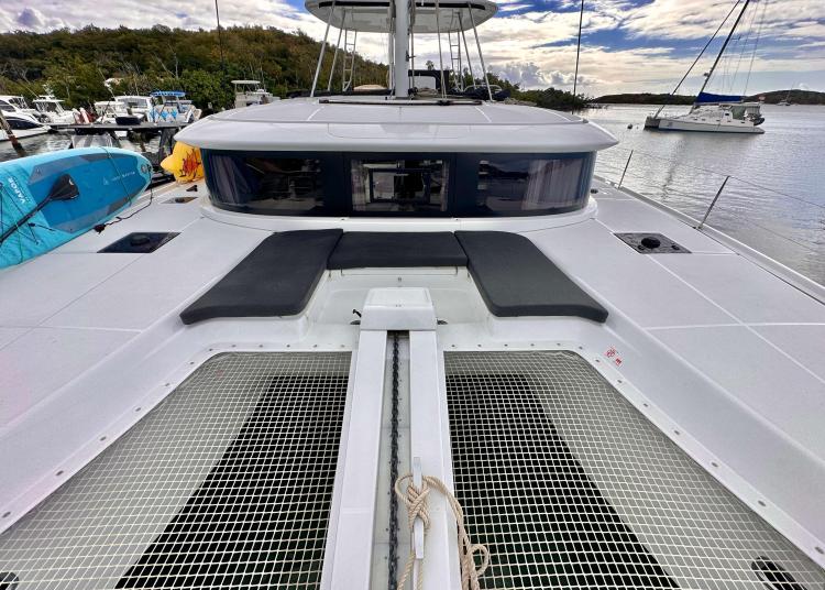 2023 Lagoon 46 catamaran deck with seating, netting, and scenic marina view.