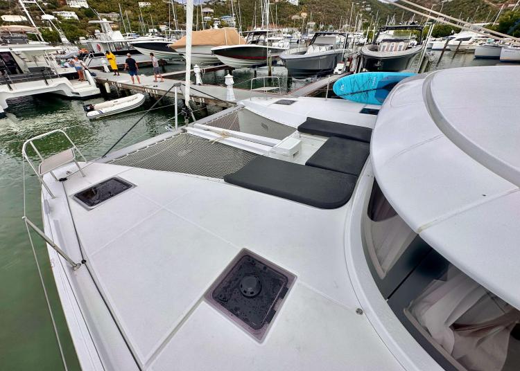 2023 Lagoon 46 catamaran docked at marina, featuring spacious deck and seating area.