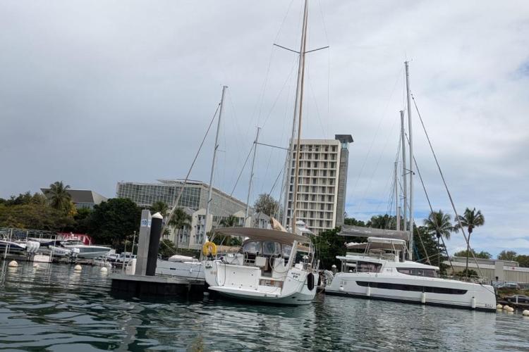 2017 Dufour 460 Grand Large yacht docked in a marina with palm trees and buildings.