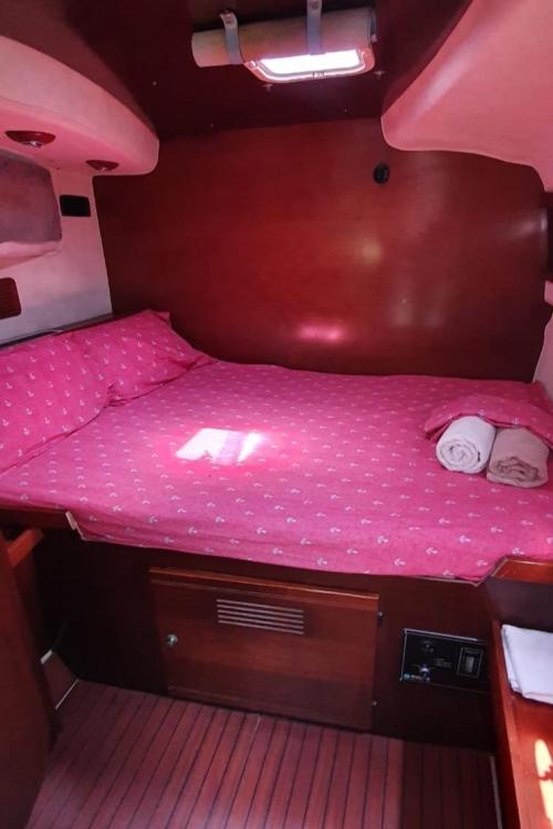 Cozy cabin interior of 1999 Fountaine Pajot Bahia 46 with pink bedding and wooden accents.