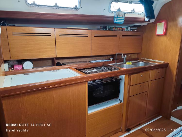Interior of 2005 Beneteau Cyclades 43.3 yacht kitchen with wooden cabinets and modern appliances.