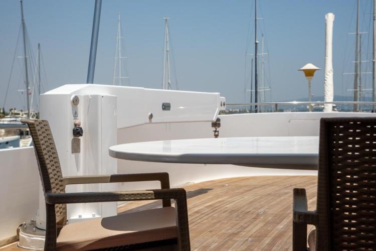 Deck view of 1972 Benetti 33 yacht with chairs and table, marina background.