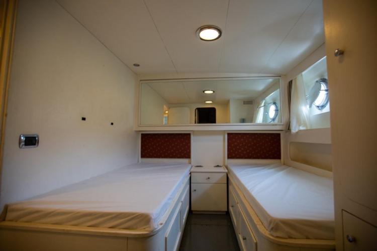 Interior cabin of 1972 Benetti 33 yacht with twin beds and porthole windows.