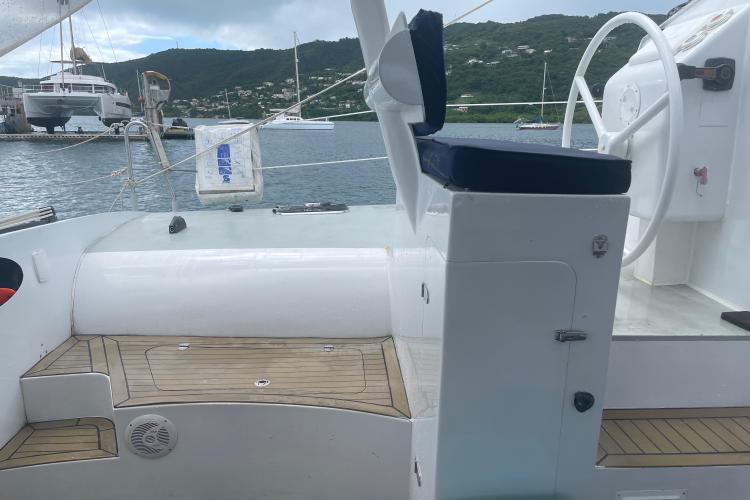 Sailboat cockpit with wooden deck, steering wheel, and blue seat, Custom KSENIA 149, 2010 model.