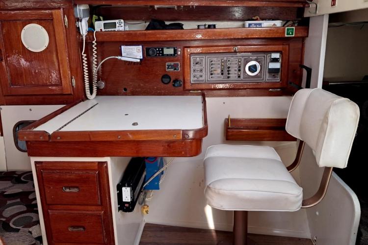 Interior of 1986 Dufour CATALINA sailboat with navigation station and white cushioned chair.