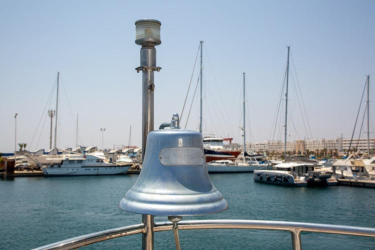 Bell on Benetti 33 yacht, 1972, with marina and sailboats in the background.