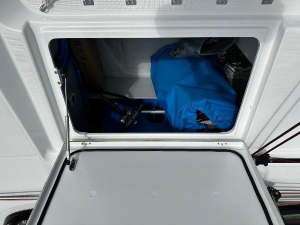 Storage compartment of 2024 Excess 11 boat, featuring blue cover and equipment inside.