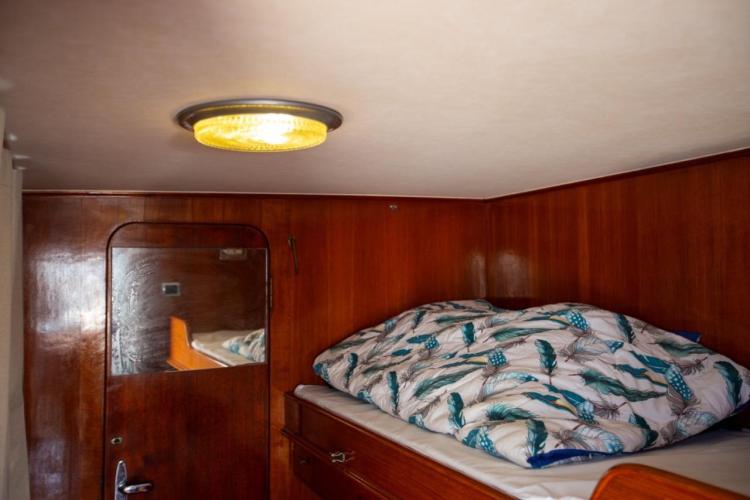 Cozy cabin interior of 1972 Benetti 33 yacht with wooden walls and patterned bedding.