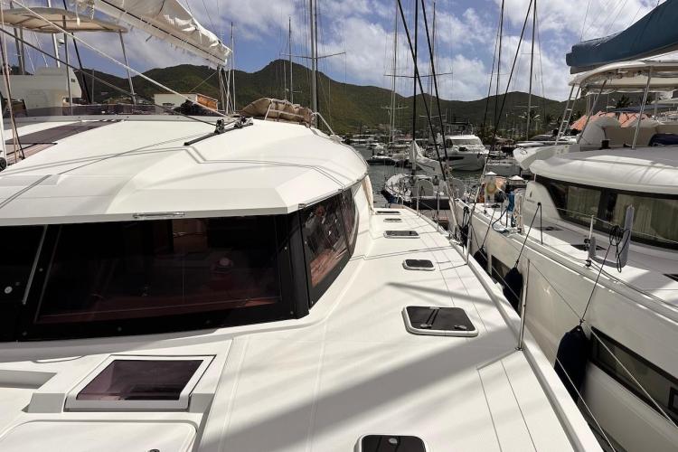 2016 Fountaine Pajot Ipanema 58 catamaran docked in a marina, surrounded by other boats.