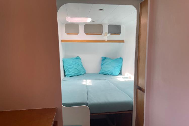 Cozy cabin interior with blue bedding in a 2010 Custom KSENIA 149 boat.