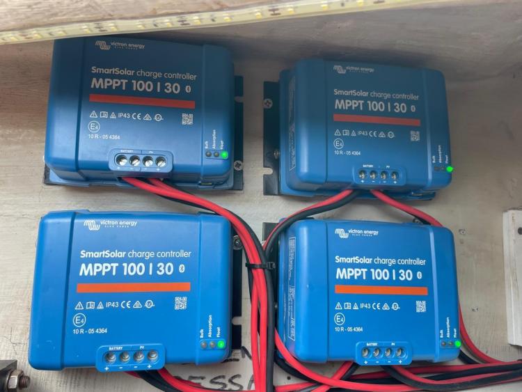 Four Victron Energy SmartSolar MPPT 100/30 charge controllers with red and black wiring.