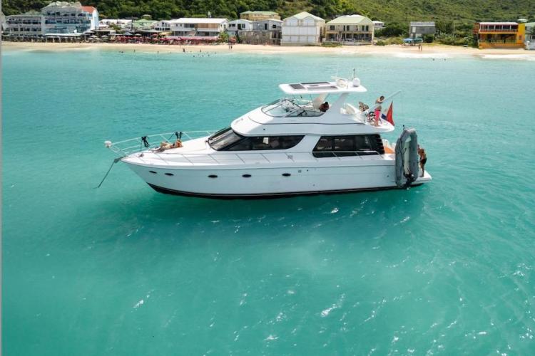 2000 Carver 530 Voyager Pilothouse yacht anchored near a scenic beach.