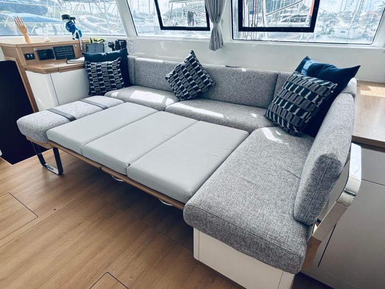 Luxurious 2024 Excess 14 yacht interior with convertible gray sofa and stylish cushions.