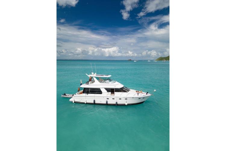 2000 Carver 530 Voyager Pilothouse yacht on turquoise water under a partly cloudy sky.