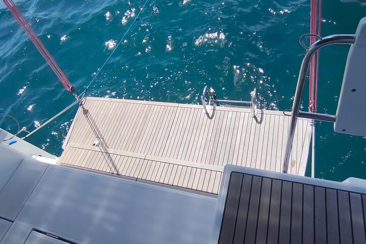 Beneteau Oceanis 46.1 yacht swim platform with ladder, 2019 model, on sparkling blue water.