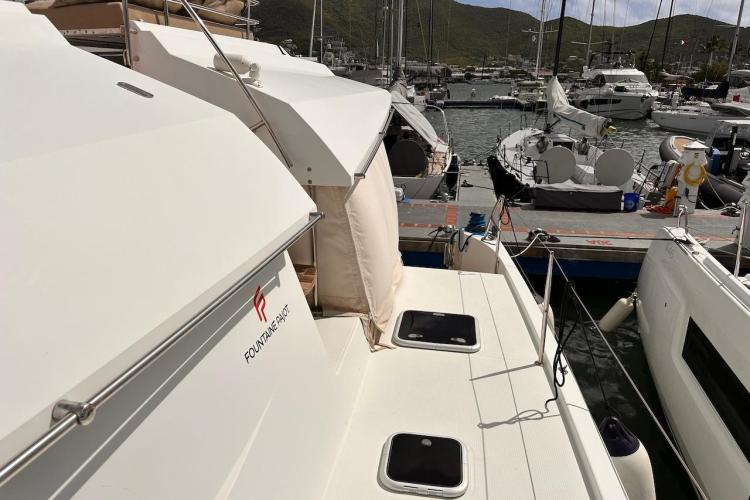 2016 Fountaine Pajot Ipanema 58 catamaran docked at a marina, surrounded by other boats.