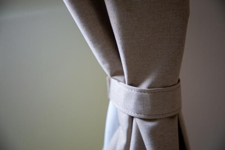 Close-up of beige curtain tied with a matching fabric strap.