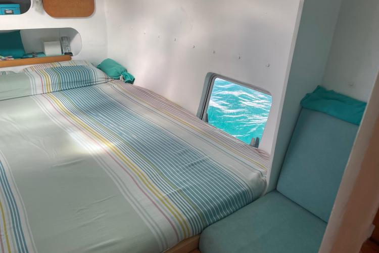 Cozy boat cabin with striped bedding and ocean view through window, Custom KSENIA 149, 2010.