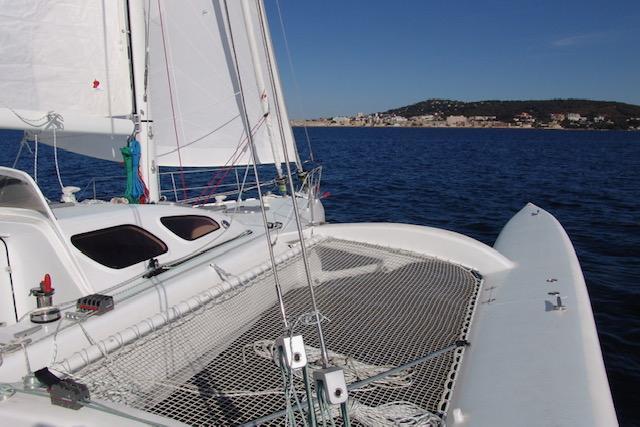 Sailing catamaran Polynésie 42, 2005 model, cruising on open sea with coastal view.