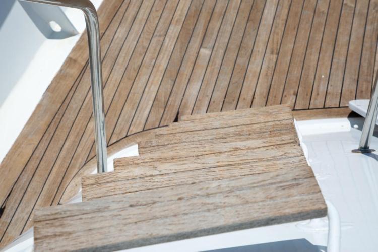 Wooden deck stairs on a 1972 Benetti 33 yacht, featuring sleek metal railings.